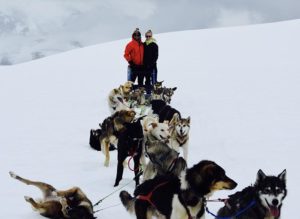 Couple with sled dogs on a glacier.
