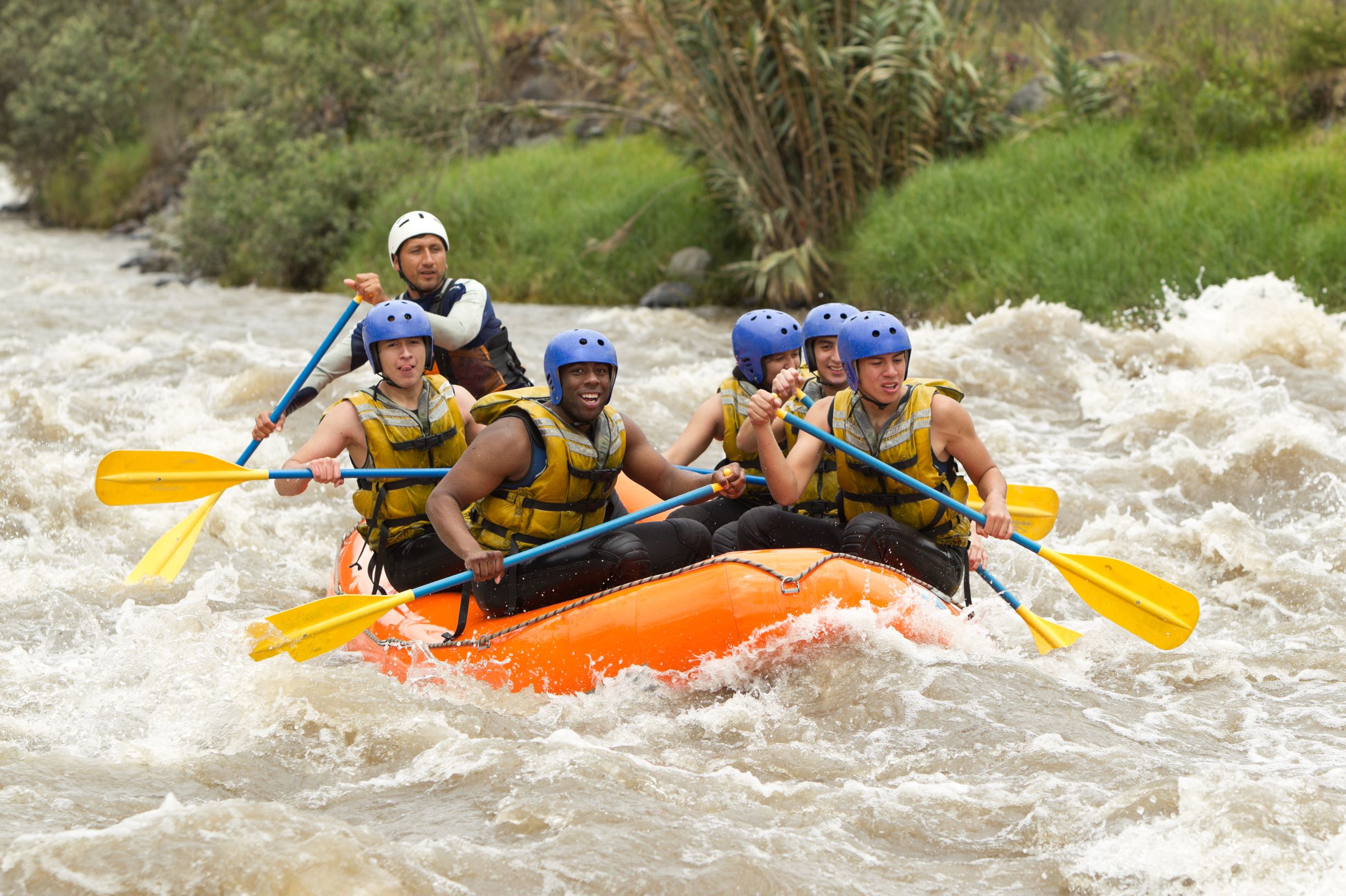 A jubilant group of young adults make their way down a seemingly treacherous river.